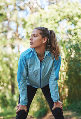 Woman, runner and thinking on break in forest fitness, training and ready with direction in...