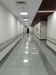 Empty modern hospital corridor, clinic hallway interior background with white chairs for patients waiting for doctor visit. Contemporary waiting room in medical office. Healthcare services concept