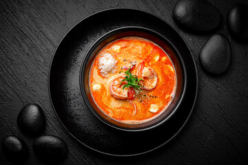 Composition of tom yam soup with shrimp and rice on black background. The Art of Japanese Cuisine. Food photography for menu and sushi bar decoration