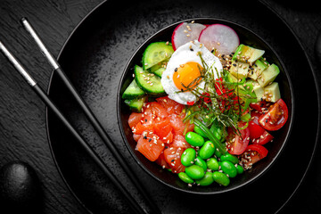 Salmon Poke bowl composition on black background. The Art of Japanese Cuisine. Food photography for menu and sushi bar decoration