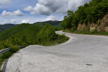 Sunny weather with beautiful and clear clouds in the sky. Visibility from the mountain at a distance of several tens of kilometers. Road bend of 180 degrees.