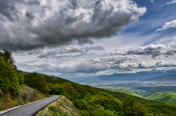 Sunny weather with beautiful and clear clouds in the sky. An asphalt road with many curves leads...