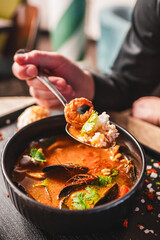 man eating thai tom yum soup in a restaurant