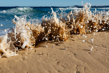 A foam wave crashing over a sandbar over on the beach