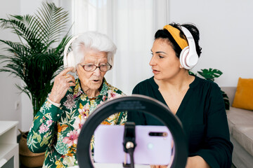 Senior woman and younger adult recording podcast at home