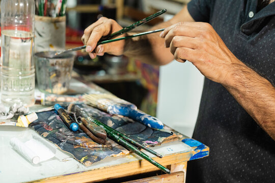 Artist selecting brushes in a colorful studio setting