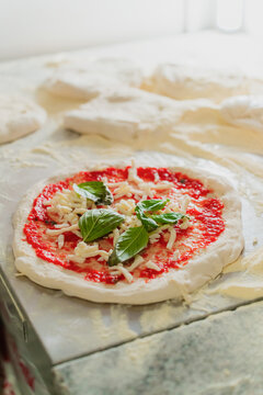 Fresh pizza base with tomato sauce and cheese being prepared