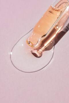 Golden serum droplet on cosmetic smudge backdrop