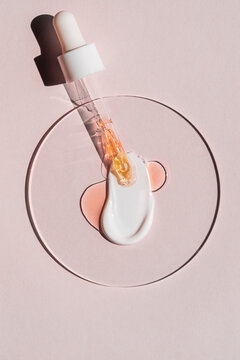 Serum dropper with cosmetic cream smear on pink