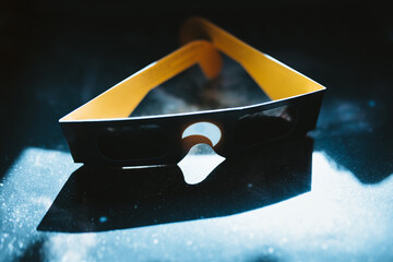 Solar eclipse glasses on a dark, dusty surface