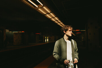Young man standing alone in an empty subway station