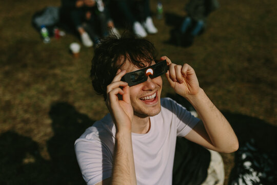 Young man excitedly using solar eclipse glasses outdoors