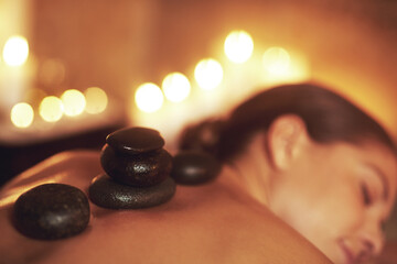 Woman, hot stone and spa relax or treatment or skin care at hotel resort or muscle tension,...