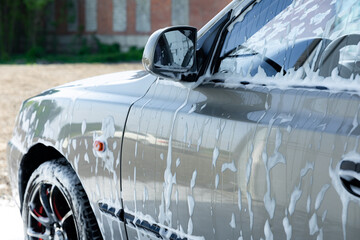 Close up car in foam. Car getting a wash with soap, car washing.