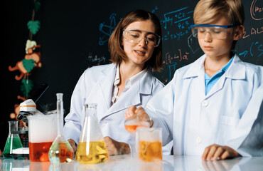 Skilled teacher watch out schoolboy in laboratory wear lab coat and glasses stand and experiment...
