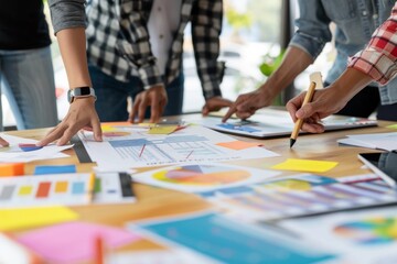 Fototapeta premium A group of professionals is seen collaborating over charts and marketing materials, engaging in strategic planning