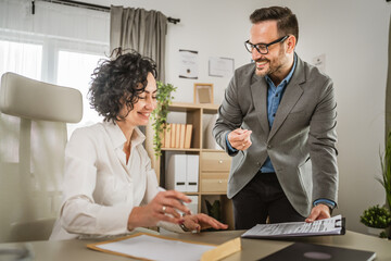 Mature woman sign insurance or contract to her colleague at office