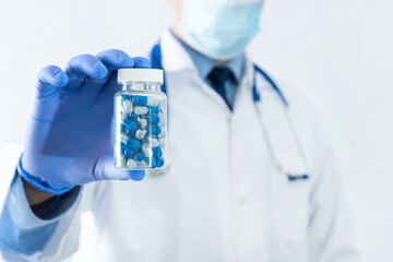 Doctor holding blue pills in bottle