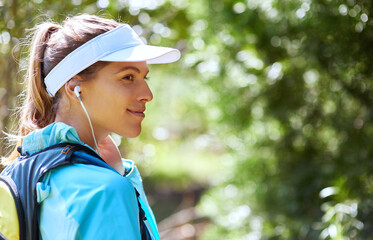 Earphones, thinking and girl hiking in nature on outdoor adventure to explore on holiday vacation. Sightseeing, woman and hiker trekking in woods for training, wellness or travel for streaming music