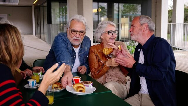 Romance in the elderly. Group of happy residents friends of a geriatric. Mature gray hair at coffee bakery cafe terrace at nursing home having fun breakfast. Caucasian senior citizens people together