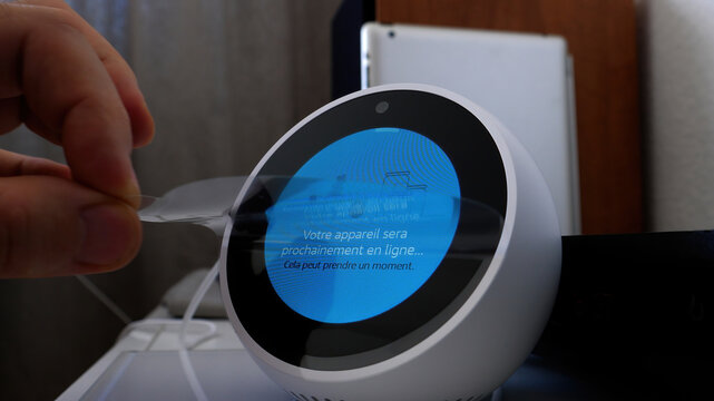 Paris, France - Jun 5th, 2020: A hand removes the protective film from an Amazon Echo Spot during the initial setup process.