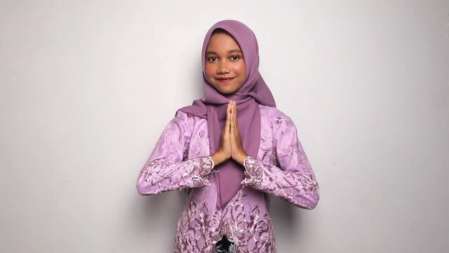smiling Indonesian teenage girls wearing kebaya and hijab gesturing greetings