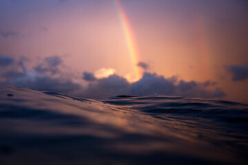 Sea level view of a beautiful rainbow captured while swimming the ocean on sunset
