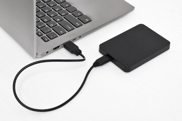 External backup hard disk drive connected to laptop on white background. external hard disk connect...
