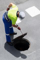 sewerage service worker checking the sewer pipe lines on  city street