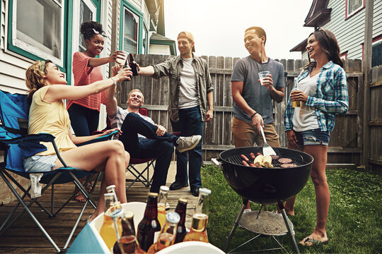 Friends, cheers and beer in backyard with bbq for social event, party or celebration with talking in home. People, drinking alcohol and toast with relax, conversation or diversity at barbecue reunion