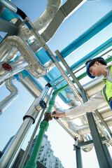 Industrial engineer adjusting pipeline valve with radio communication on construction site....
