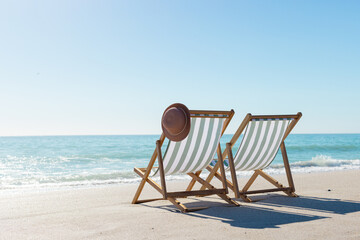 Obraz premium At beach, two empty chairs facing sea, hinting at relaxation