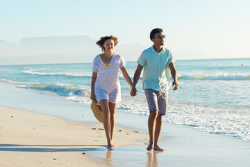 Obraz premium At beach, biracial couple holding hands, walking