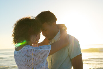 Obraz premium At beach, biracial couple embracing gently, both with curly hair