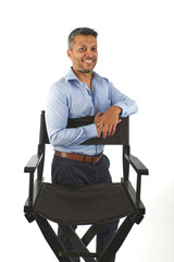A man is posing in front of a chair