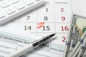 Calendar with date reminder about tax day, documents, pen, calculator and money, closeup