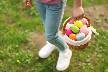 Easter celebration. Little girl holding basket with painted eggs outdoors, closeup