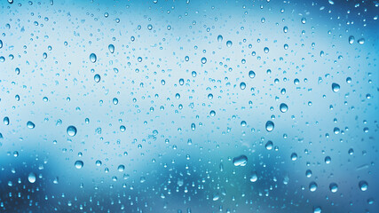 Raindrops on a glass window with a blue background.