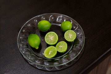A few limes on a plate, some of which are cut to be served with the food in details indicating healthy food.