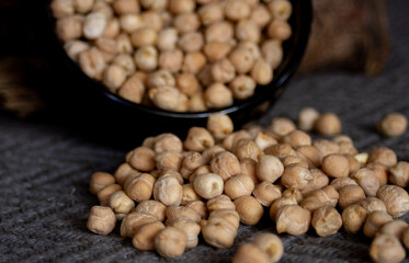 Chickpeas falling from a bowl . Dark background. Close-up photo