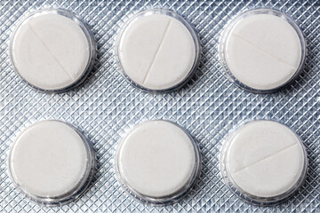 A pack of pills with a white label and a silver background