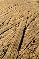 Multiple tyre tire tracks crisscrossing over a sandy surface