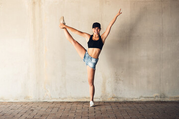 Girl, street dancer and hip hop in city with balance, steps and lift leg in portrait at training. Woman, person and dancing for culture, art and stretching with rhythm for performance on sidewalk
