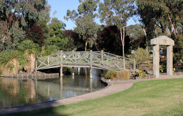Wooden bridge spanning a serene pond of water surrounded by trees and plants at Riverside Park in Swan Hill, Victoria, Australia © Tammy Walker