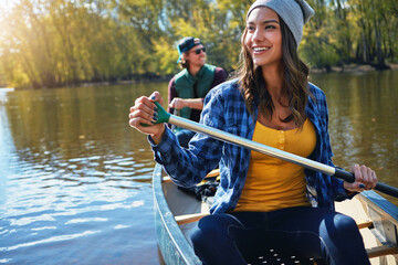 Couple, canoeing and lake for outdoor holiday exploring or rowing adventure, environment or...