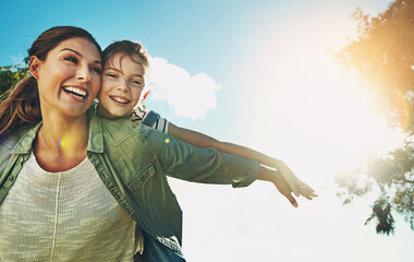 Mother, daughter and plane on back with playing outdoor in nature with blue sky, sunlight and...