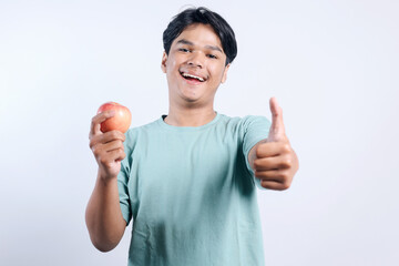 Excited Young Asian Guy Showing Thumb Up And Holding Apple Isolated On White Background