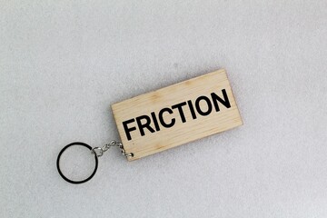 wooden tag or keychain with the word Friction. the resistance that one surface
