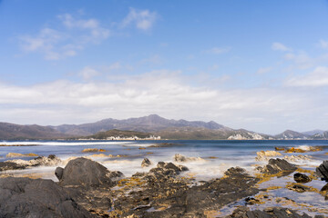 sailing on a yacht in the australian in the remote forest wilderness in spring, with waves breaking on a beach on the australian coastline