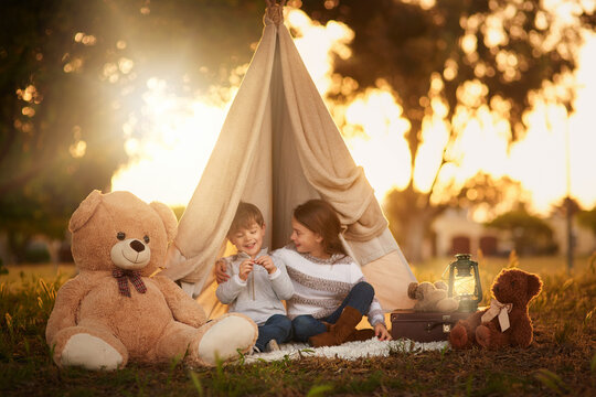 Teepee, children and fun in garden tent outdoor in nature for camping, playing and adventure with sunlight. Cloth, light and fantasy house for kids in forest with imagination, suitcase and teddy bear